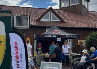 Unter einem faltbaren Pavillion stehen Menschen. Hier ist die Anmeldung für den inklusiven Wassersport-Event.